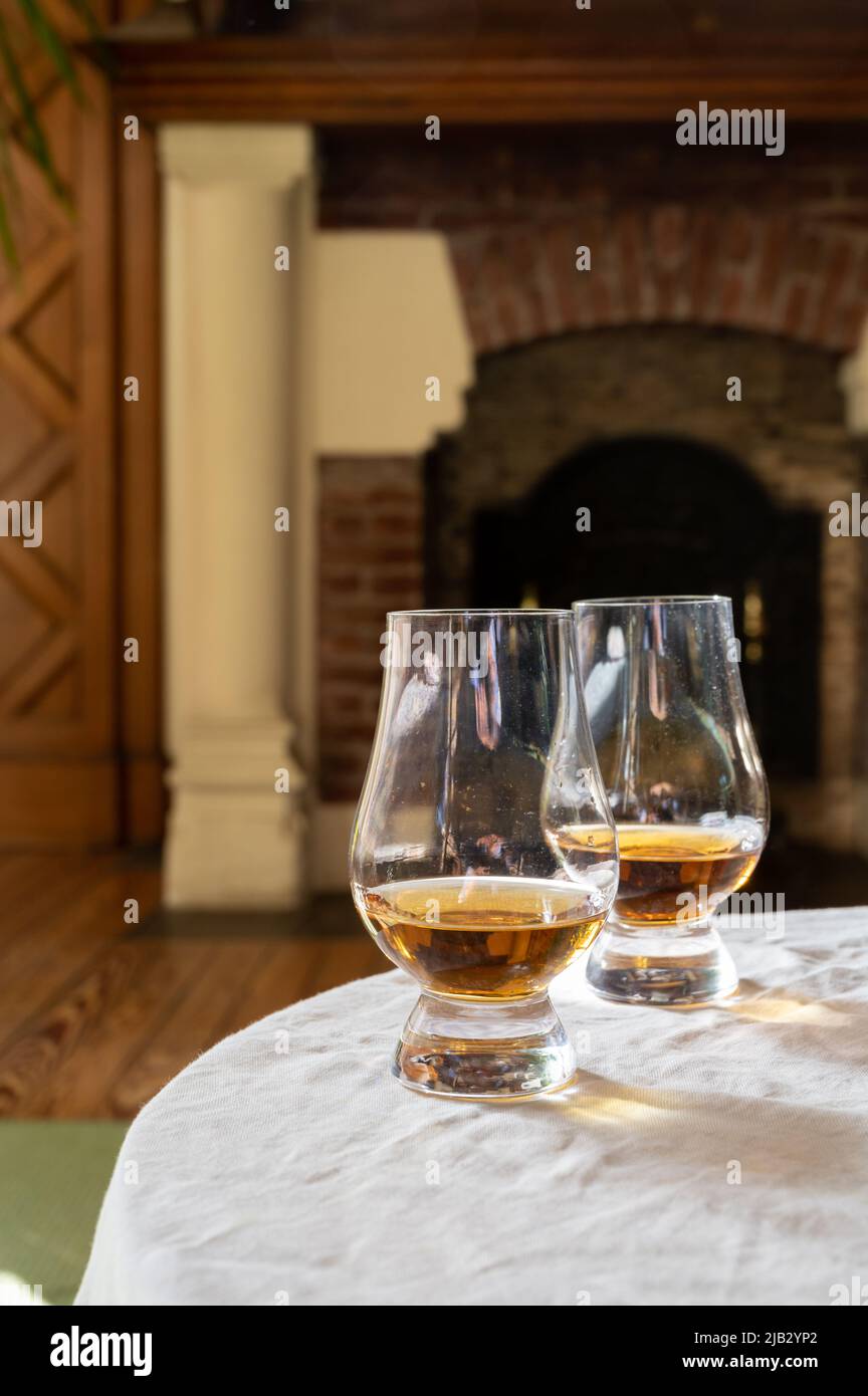 Two drams of scotch whiskey with view on fireplace in old house on