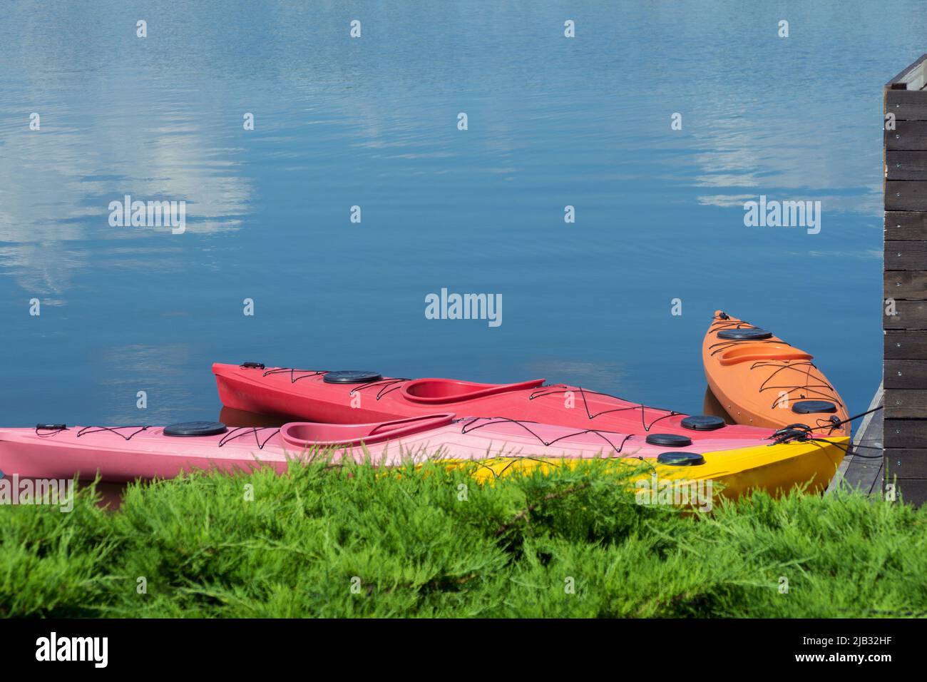 Bright colored kayak from plastic boats in the yacht club. Active summer vacation on the water on a bright sunny day. Stock Photo