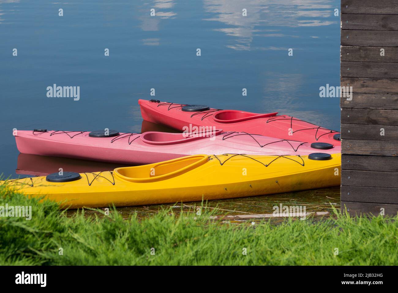 Bright colored kayak from plastic boats in the yacht club. Active summer vacation on the water on a bright sunny day. Stock Photo