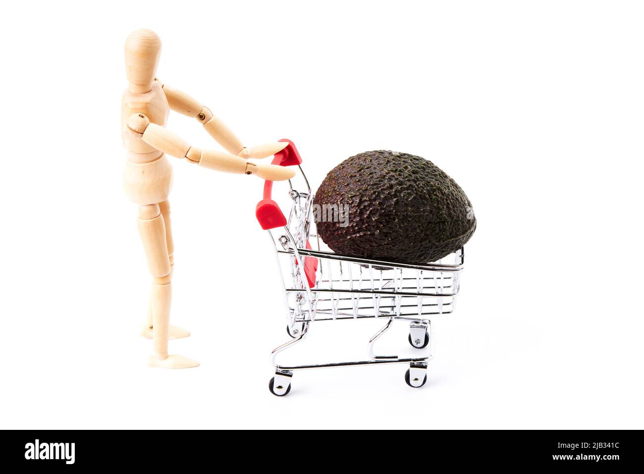 Dummy pushing a shopping cart with avocado on a white background. Shopping concept. Healthy shopping Stock Photo
