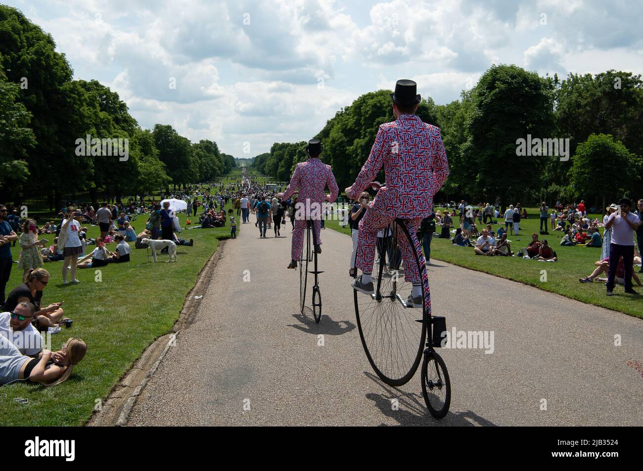 Windsor, Berkshire, UK. 2nd June, 2022. Two men randomly cycle down the Long Walk on Penny Farthing Bicycles and wearing Union Jack suits. Thousands of people went to the Long Walk today to picnic, celebrate and watch the Red Arrows flypast. Windsor was packed with locals, tourists and visitors today celebrating Her Majesty the Queen's Platinum Jubilee. Credit: Maureen McLean/Alamy Live News Stock Photo