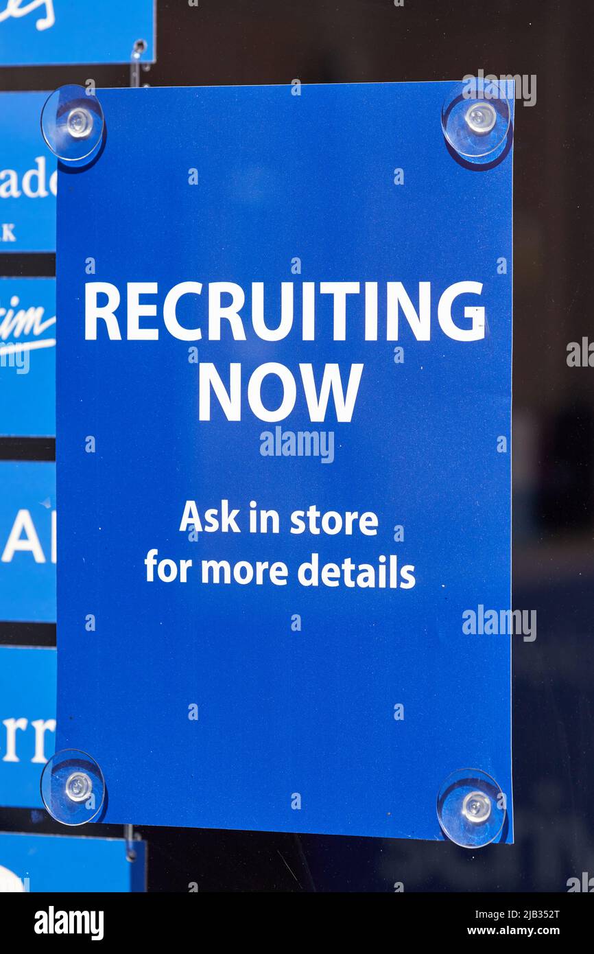 Ringwood, UK. - 22 May 2022: A recruiting now sign in a shop window. This month it was announced that unemployment is at its lowest level since 1974 after Office for National Statistics figures reveal the number of jobless people has dropped to 3.7 per cent in the first three months of the year. Stock Photo