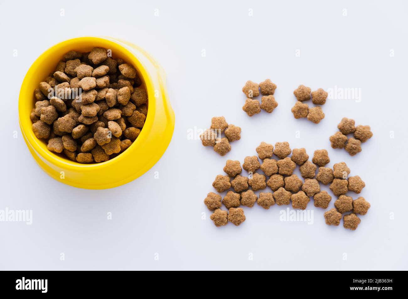 top view of paw shape made of dry pet food near bowl isolated on white Stock Photo