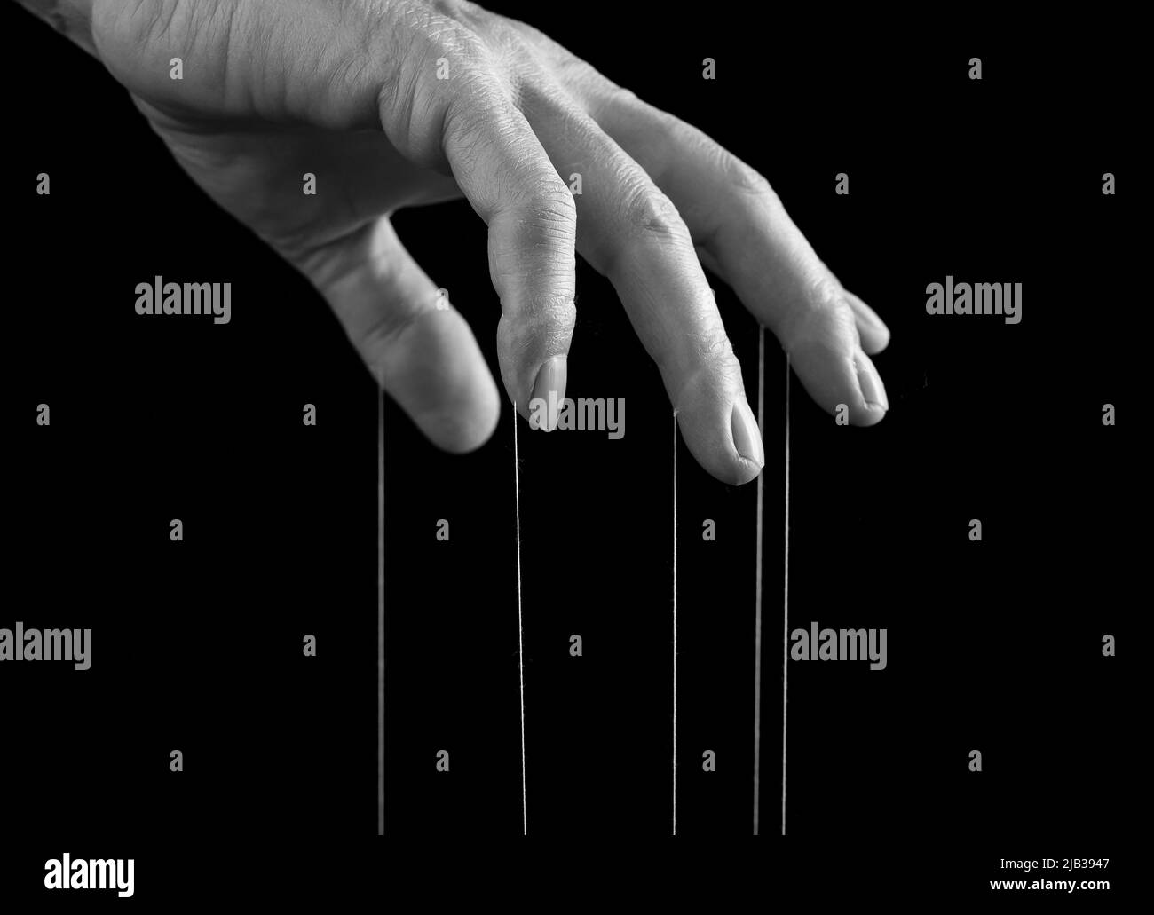 Influence, manipulation concept. Man hand with strings on fingers. Male suffering from drug, gambling, internet addiction or physical, emotional stress. Black and white. High quality photo Stock Photo