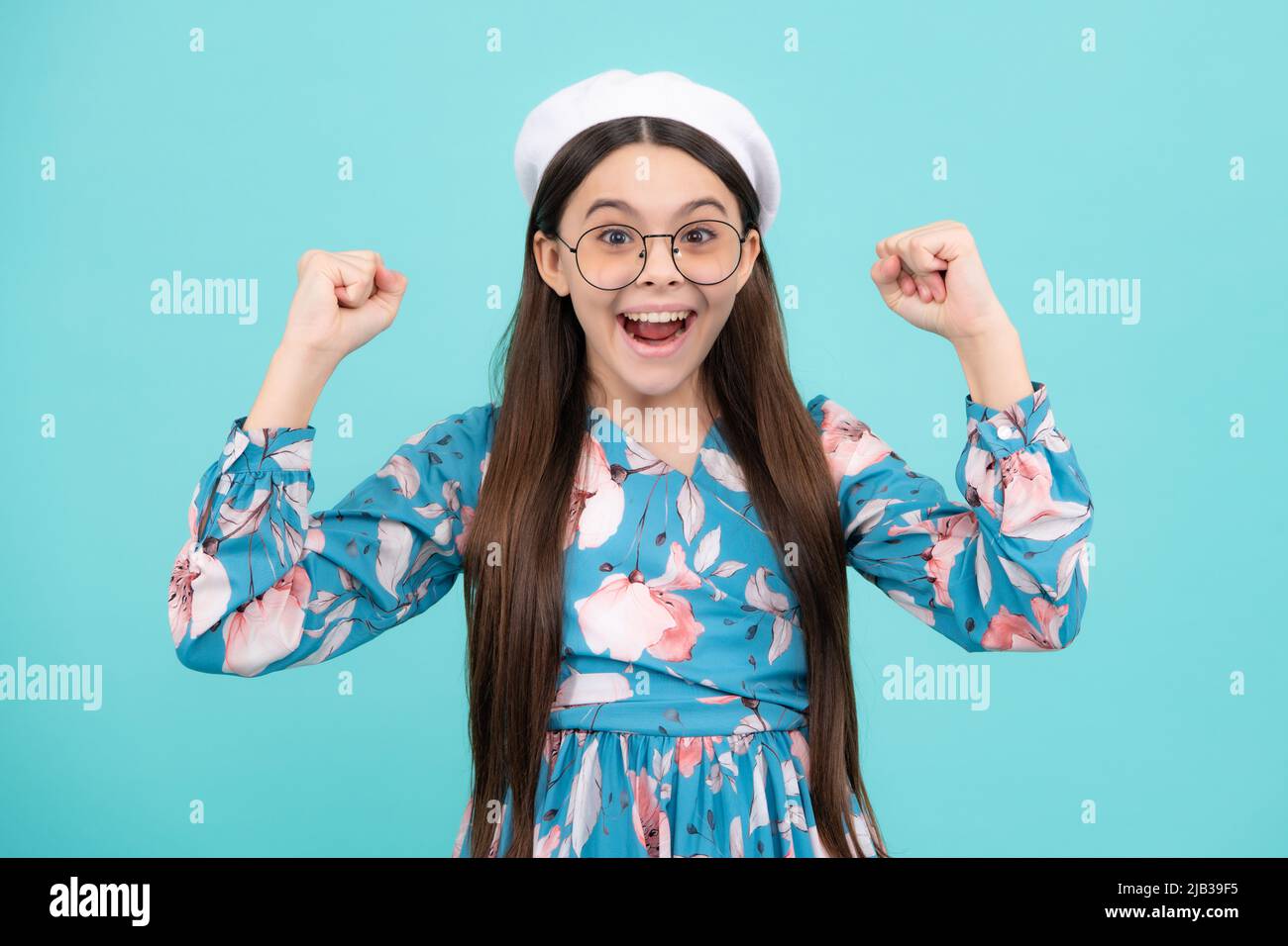 Studio portrait of teenager child doing winner gesture. Kid rejoicing, yes victory champion gesture, fist pump. Excited teenager, amazed and cheerful Stock Photo