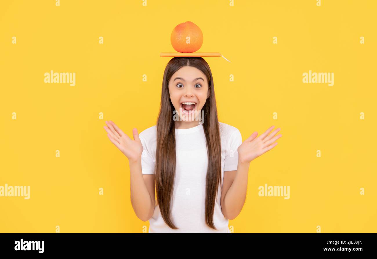amazed teen girl with book and grapefruit on yellow background, health Stock Photo