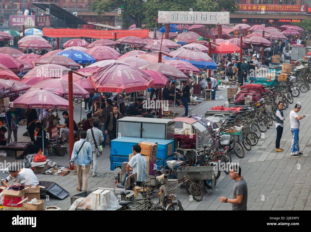 Traders at the Panjiayuan flea market in Beijing with a large number of bicycle rickshaws parked in a line. Stock Photo