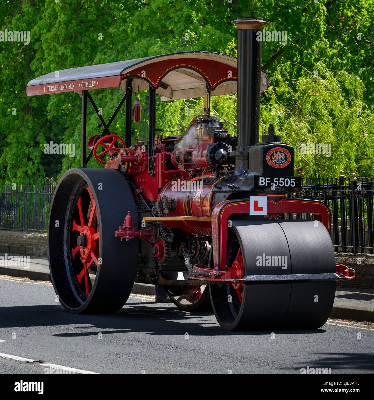 Red black stationary heavy steam-powered vehicle parked at roadside (L-plate & reg number on front) - Burley-in-Wharfedale, West Yorkshire England UK. Stock Photo