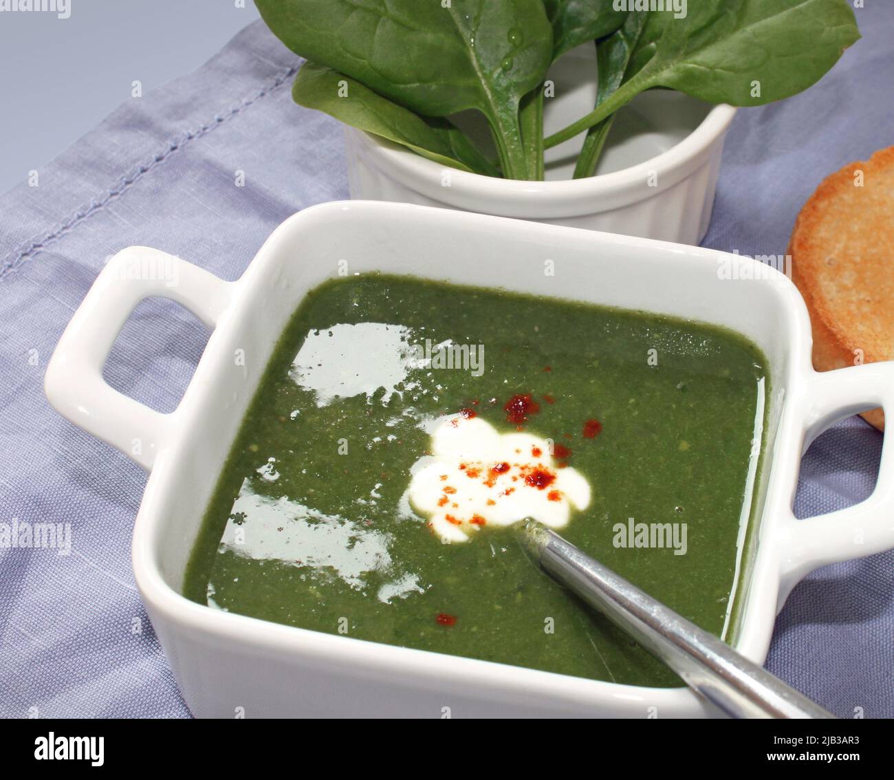 A bowl of freshly made spinach soup on a lavender linen placemat. Stock Photo