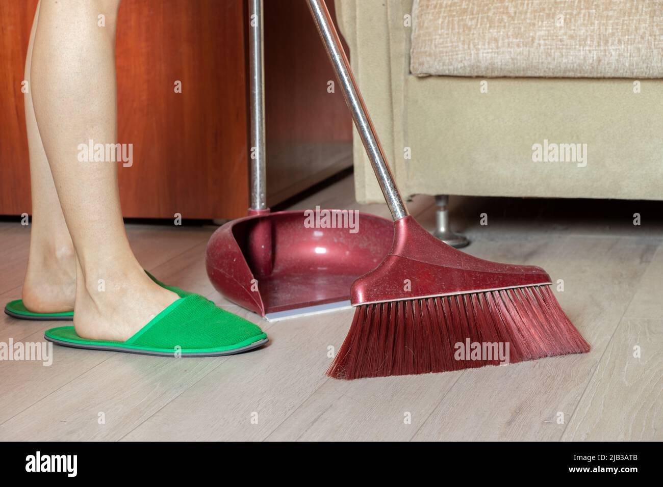 girl sweeps the floor with a brush at home, feet on the floor, cleaning