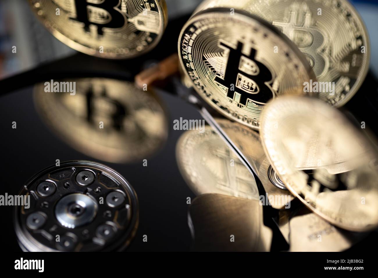 Bitcoin reflecting on HDD platter, gold BTC coins closeup view. Hard drive with crypto currency. Digital money concept Stock Photo