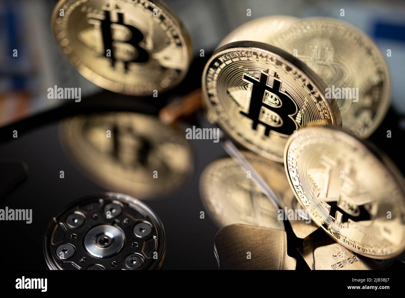 Bitcoin reflecting on HDD platter, gold BTC coins closeup view. Hard drive with crypto currency. Digital money concept Stock Photo