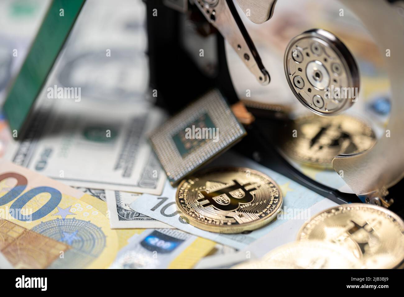 Bitcoin reflecting on hard drive platter next to CPU and on top of euro and dollar banknotes. Cryptocurrency mining concept, blockchain technology. Stock Photo
