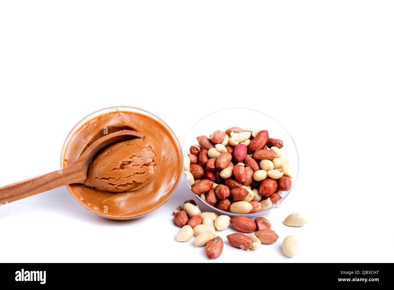 Peanuts with peanut paste in a wooden spoon. Isolated on a white background Stock Photo