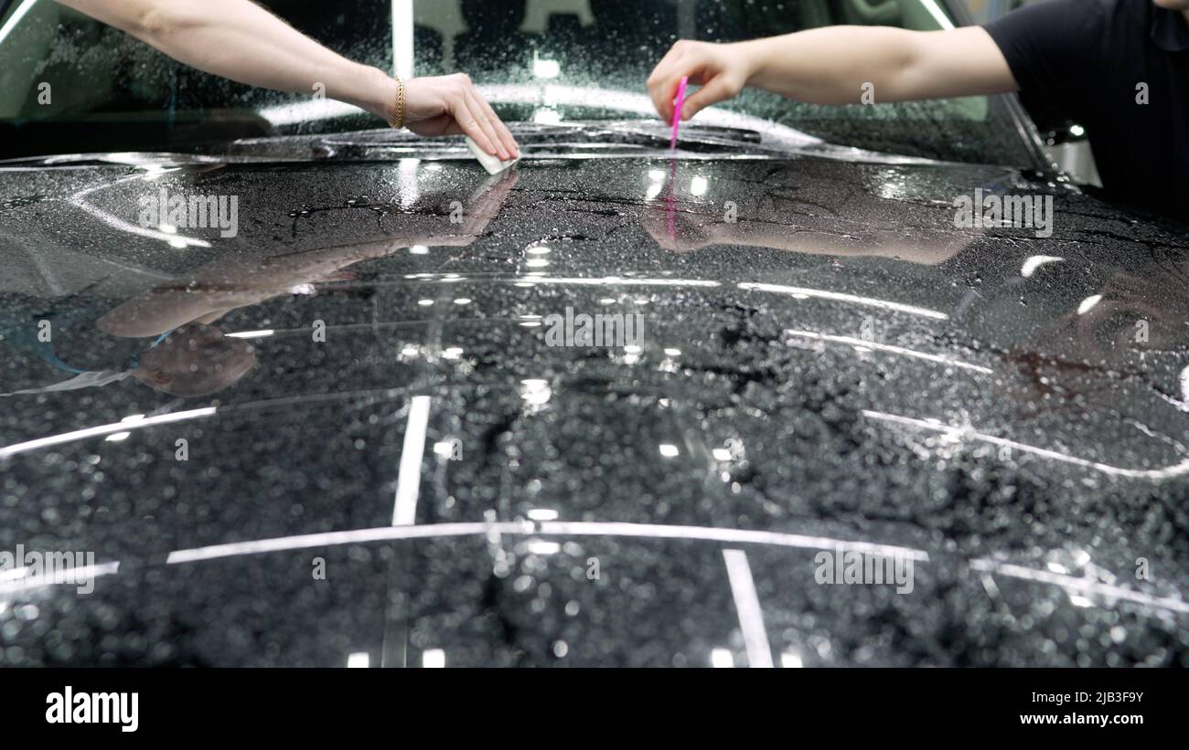 Masters stick a protective film on the hood of the car. Car wrapping