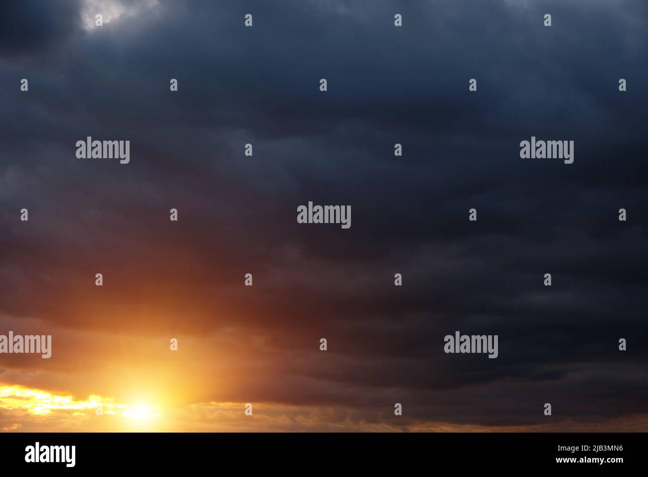 Thunderclouds with breaking rays sun at sunset Stock Photo