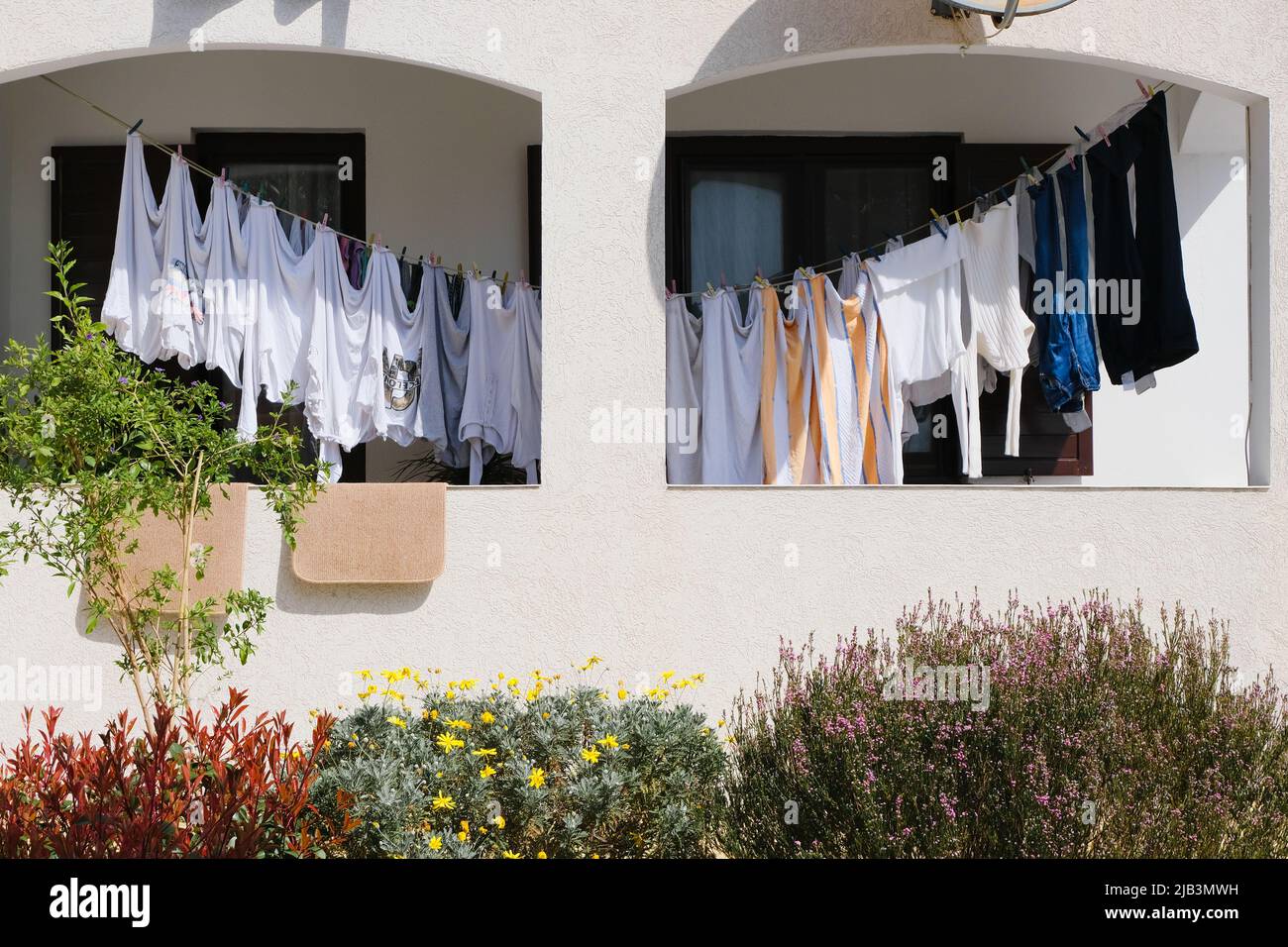 laundry hanging on a balcony clothesline on white house wall background