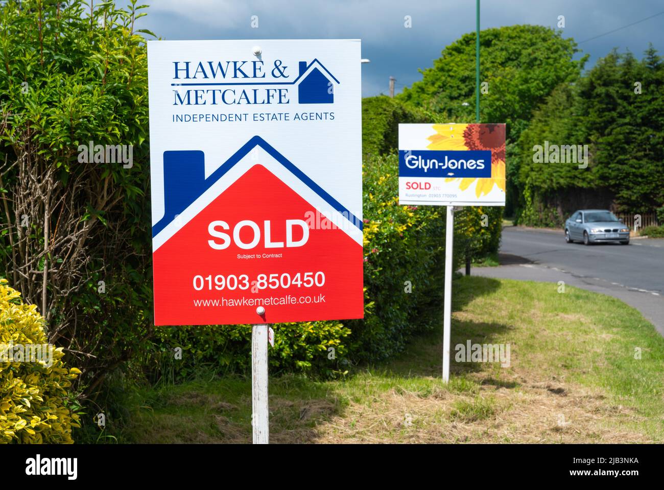 Estate agent sign (Hawke & Metcalfe) and another for Glyn Jones estate agents showing houses or properties sold. House sold signs in England, UK. Stock Photo