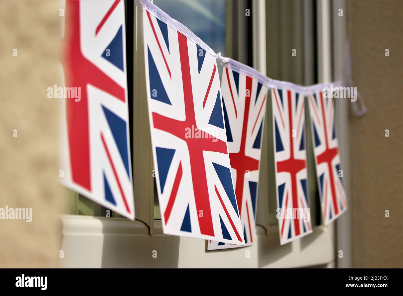 Hanging banner of union jacks, flag of the United Kingdom, seen outdoors. Hung for the platinum jubilee. Stock Photo