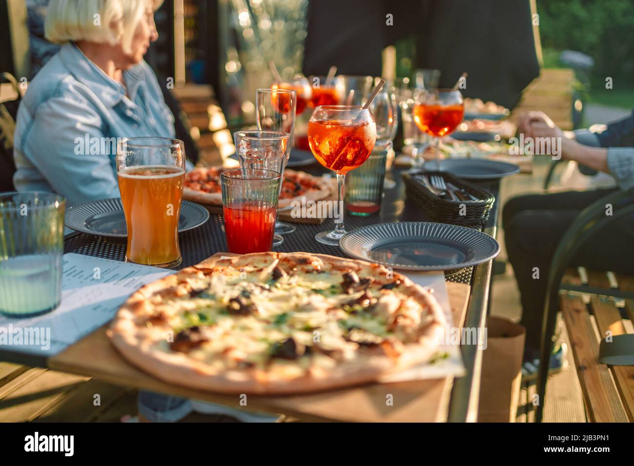 Healthy restaurant lunch for vacation couple in summer.Served banquet table with fresh pizza food, cocktail drinks at street cafe at sunrise time Stock Photo