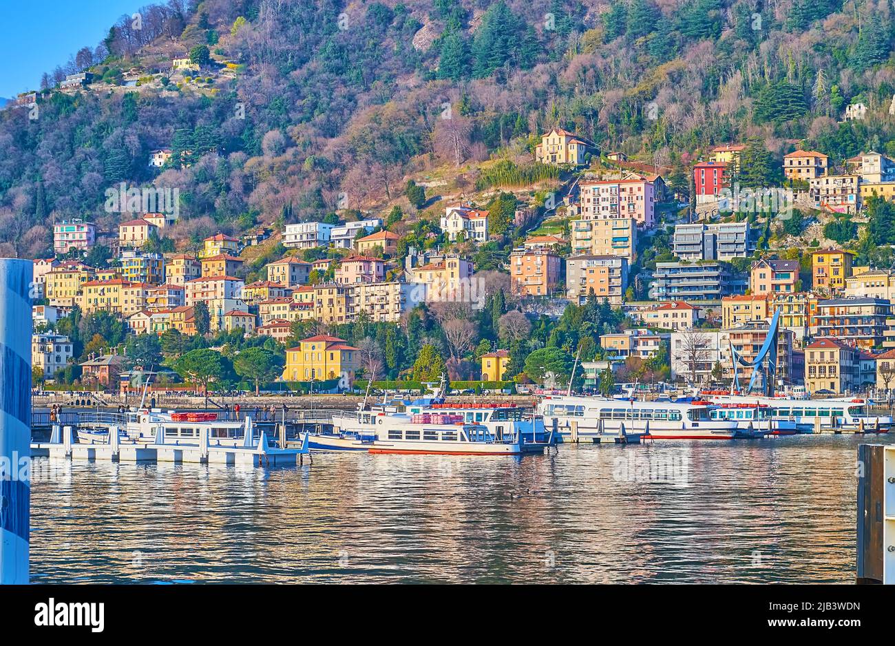 The boats, moored on Lake Comoagainst the colorful housing of Como at the foot of Monte Boletto, Lombardy, Italy Stock Photo