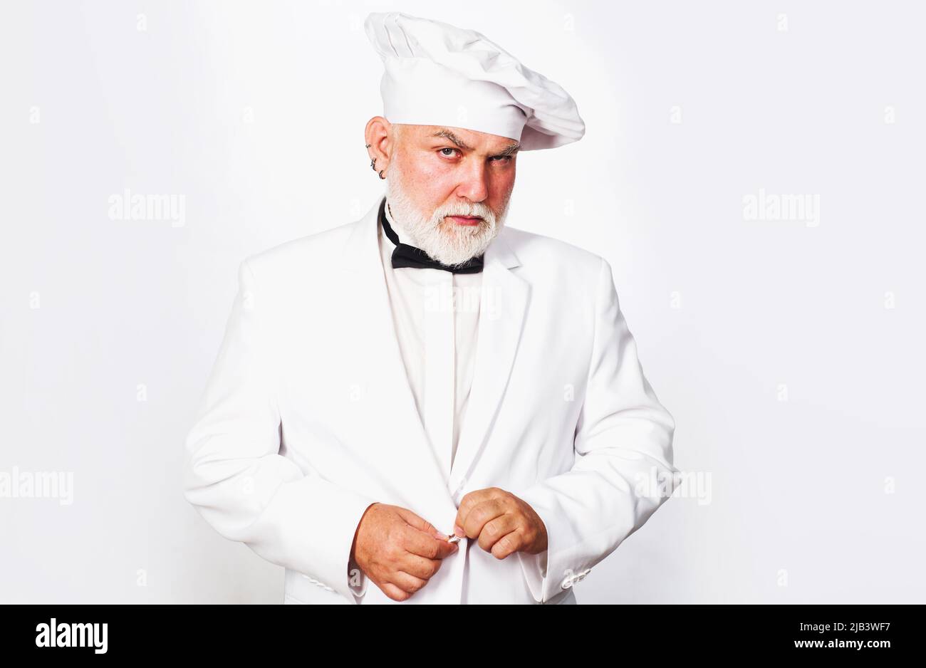 Serious bearded chef, cook or baker in white uniform and hat. Cooking. Kitchen advertising. Stock Photo