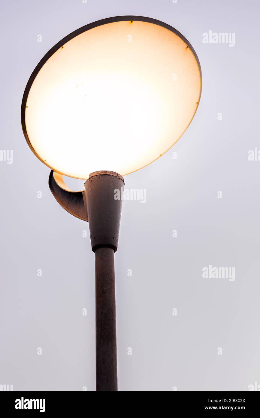Round street lamp shines with yellow light at twilight Stock Photo Alamy