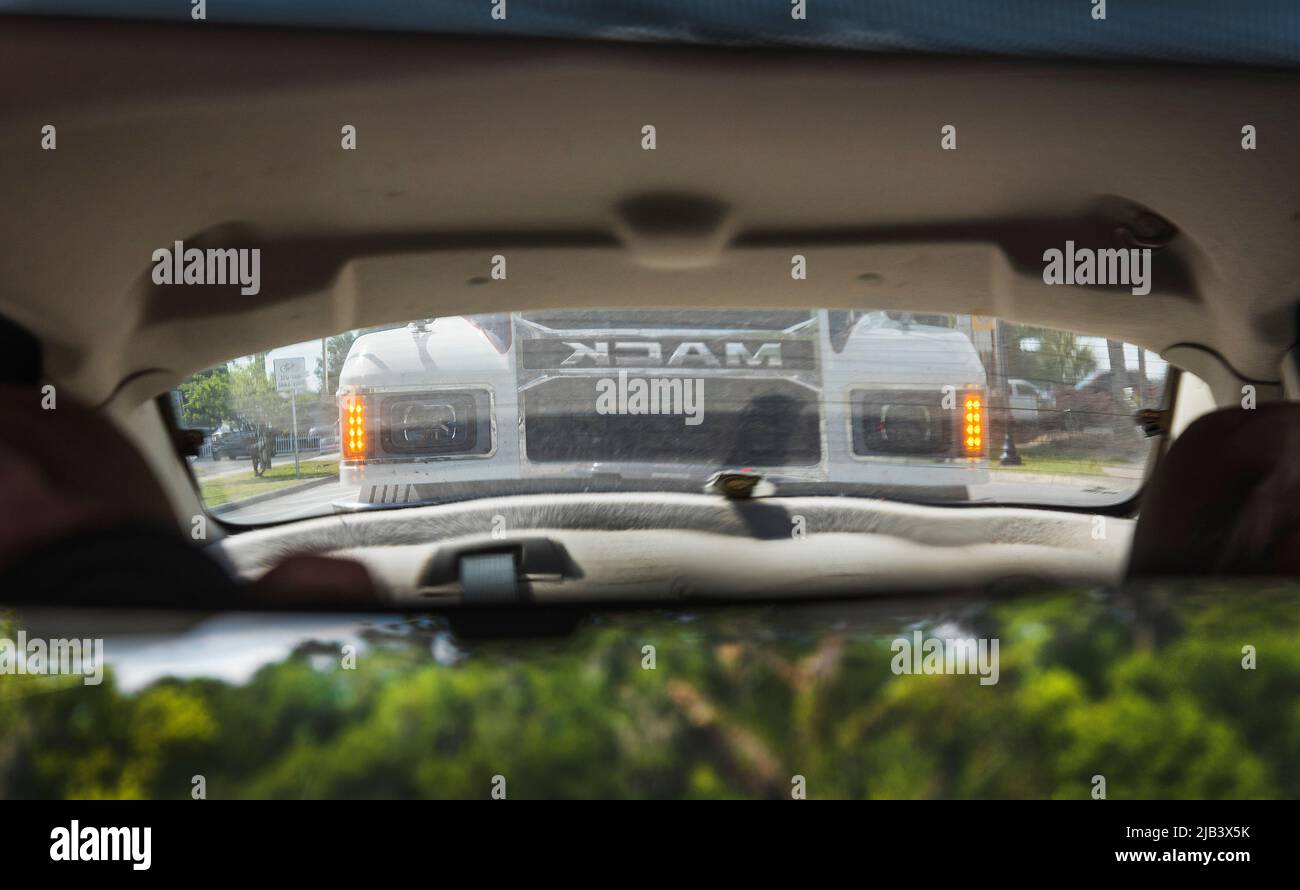Large Mack Truck semi, looming in the rearview mirror of a car.....very closely. Stock Photo