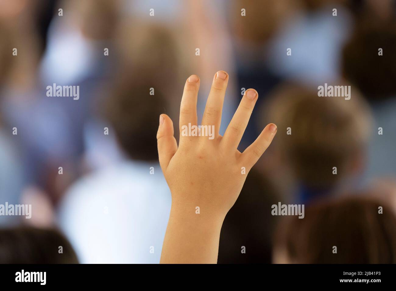A child raises their hand in the air during a lesson in a school classroom. Stock Photo