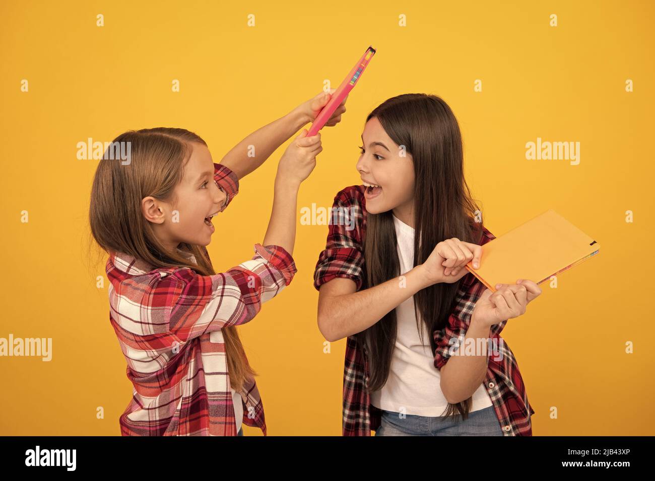 cheerful children in casual checkered shirt having fun with notebooks, best friend Stock Photo