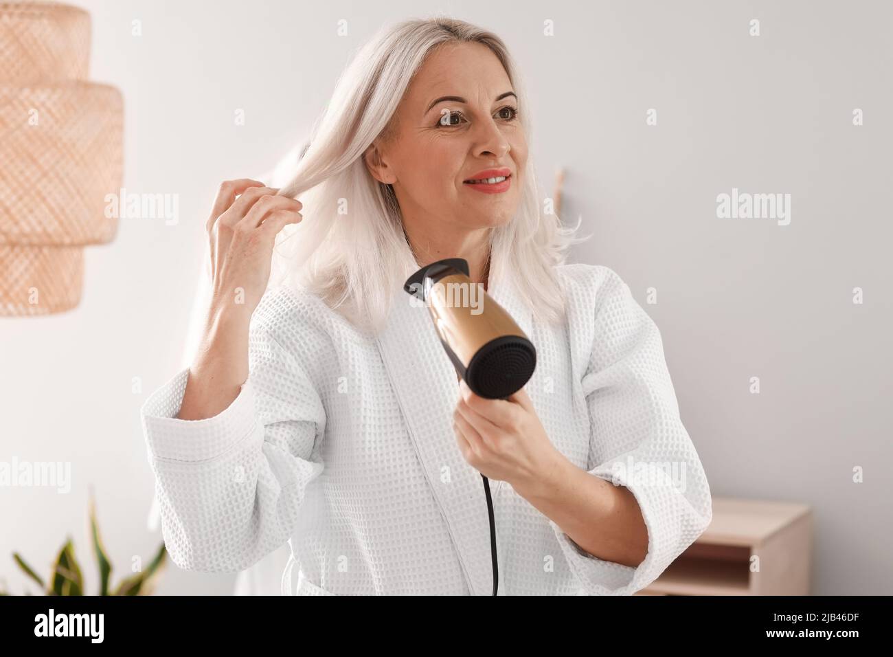 Mature woman blow drying hair hi-res stock photography and images - Alamy