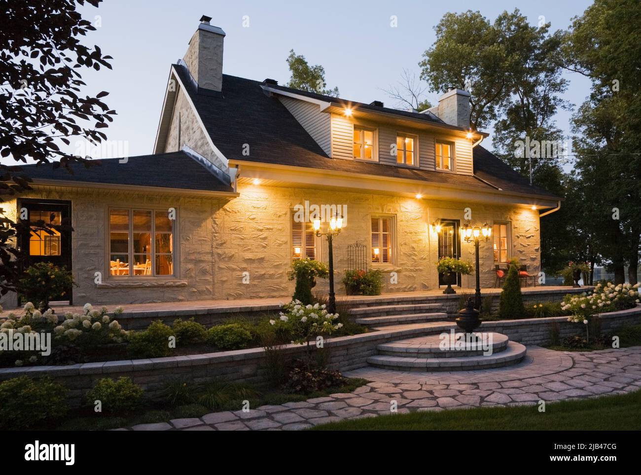 Old Circa 1840 Canadiana Style Home With Coat Of Grey Cement Applied   Old Circa 1840 Canadiana Style Home With Coat Of Grey Cement Applied Over Cut Stone Cladding At Dusk 2JB47CG 