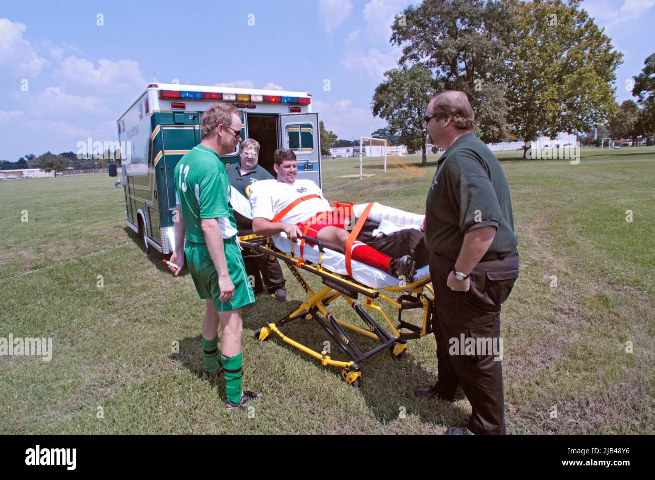 Soccer player, adult man with a broken leg is put in ambulance on stretcher by medics during Game which was co-ed, both men and women on the teams Stock Photo
