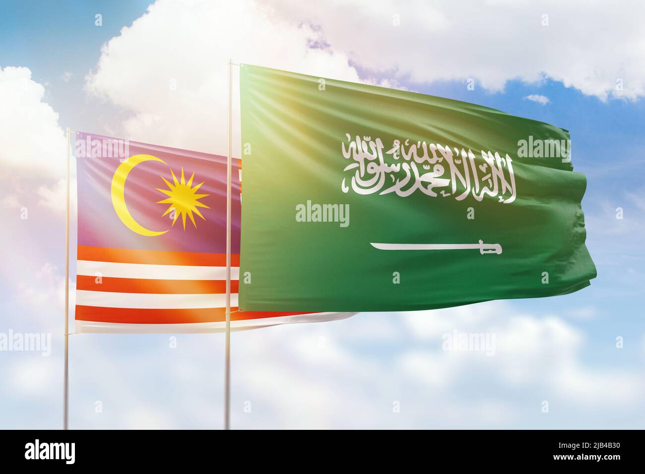 Sunny blue sky and flags of saudi arabia and malaysia Stock Photo