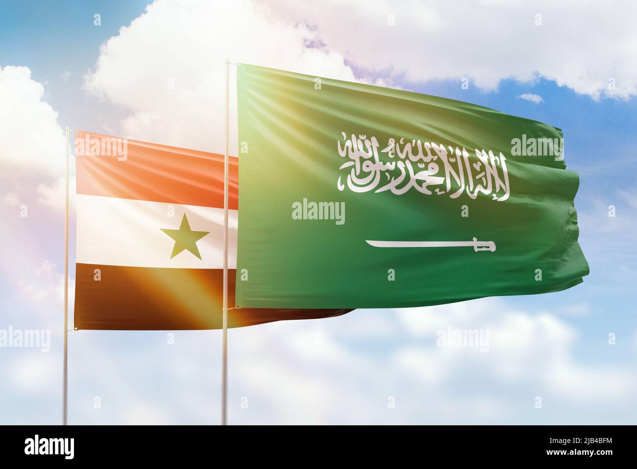 Sunny blue sky and flags of saudi arabia and syria Stock Photo