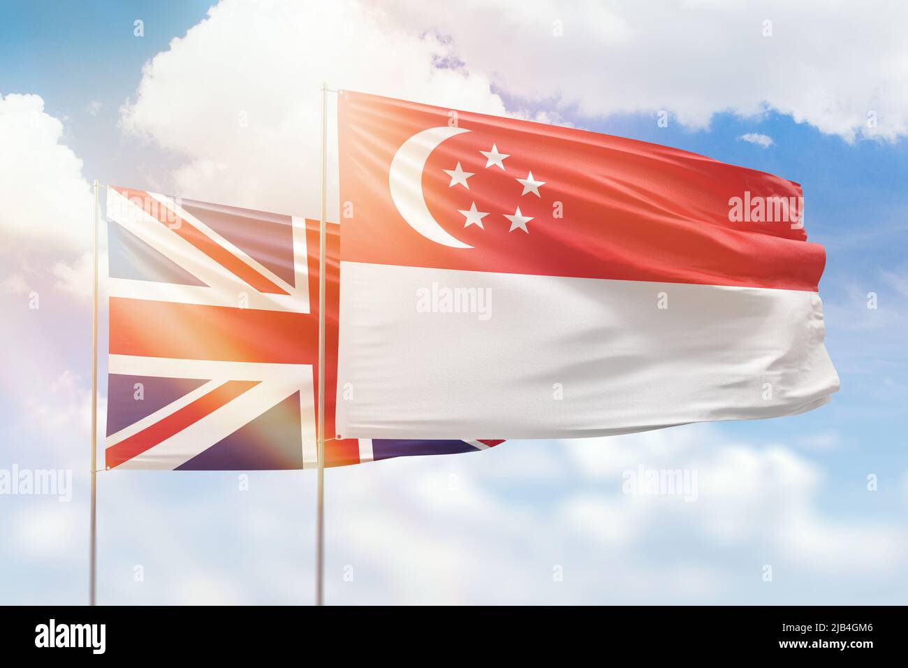 Sunny blue sky and flags of singapore and united kingdom Stock Photo