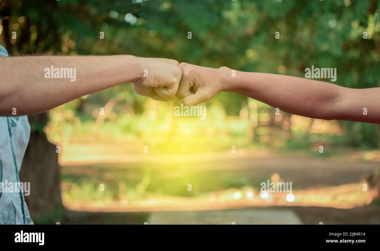 Two young men clashing their fists, image of two young men bumping their fists in a friendly way, close up of two fists bumping in a friendly way Stock Photo