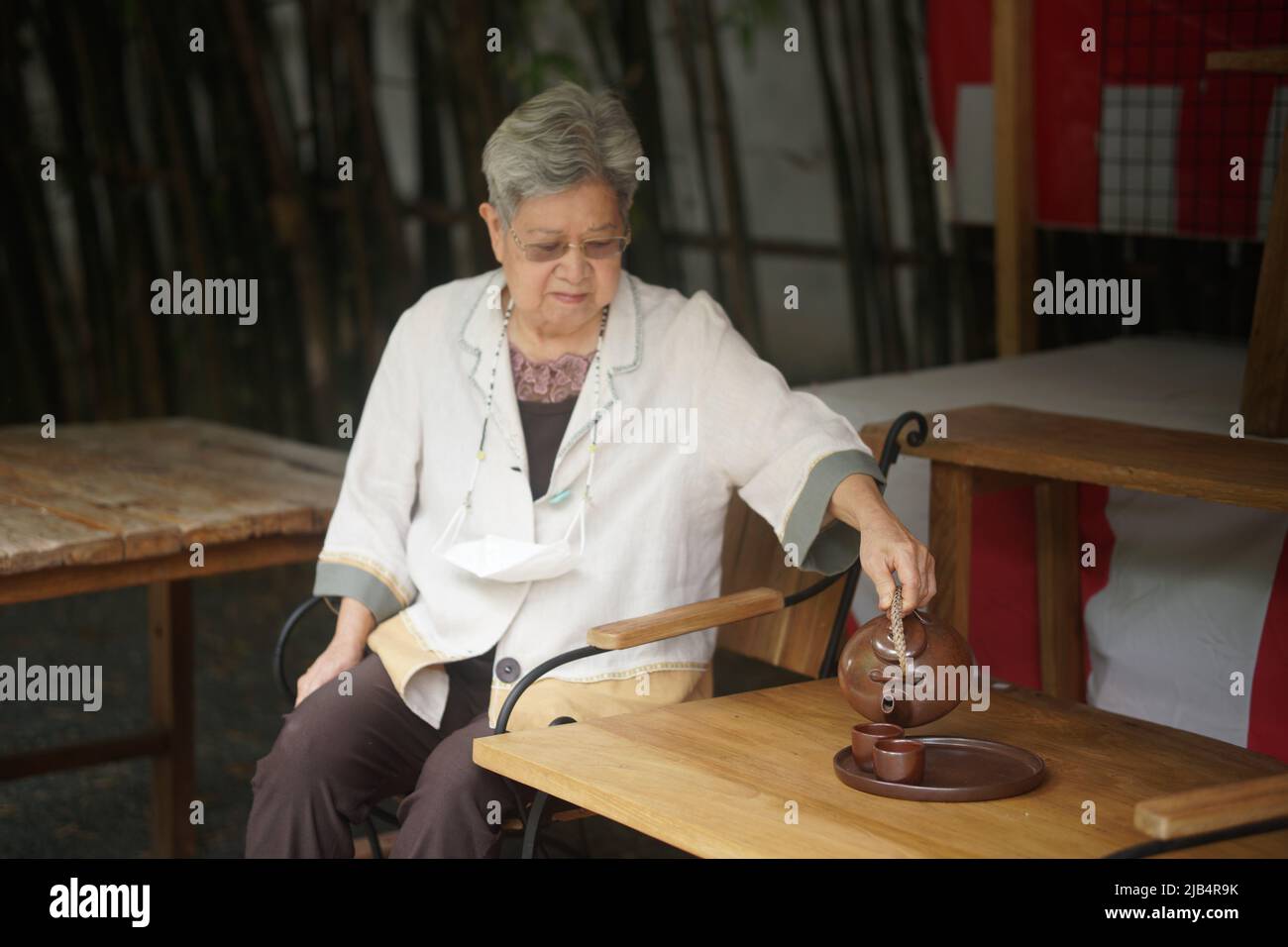 asian old elderly female elder woman drinking hot tea in garden. senior leisure lifestyle Stock Photo