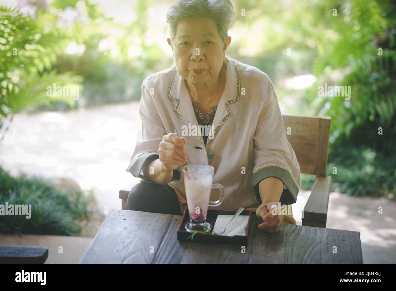 old elderly senior elder woman eating ice cream on terrace. mature retirement lifestyle Stock Photo