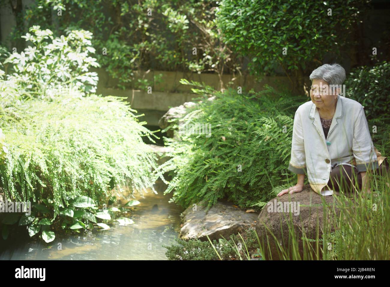 old elderly elder senior woman resting relaxing walking in garden Stock Photo