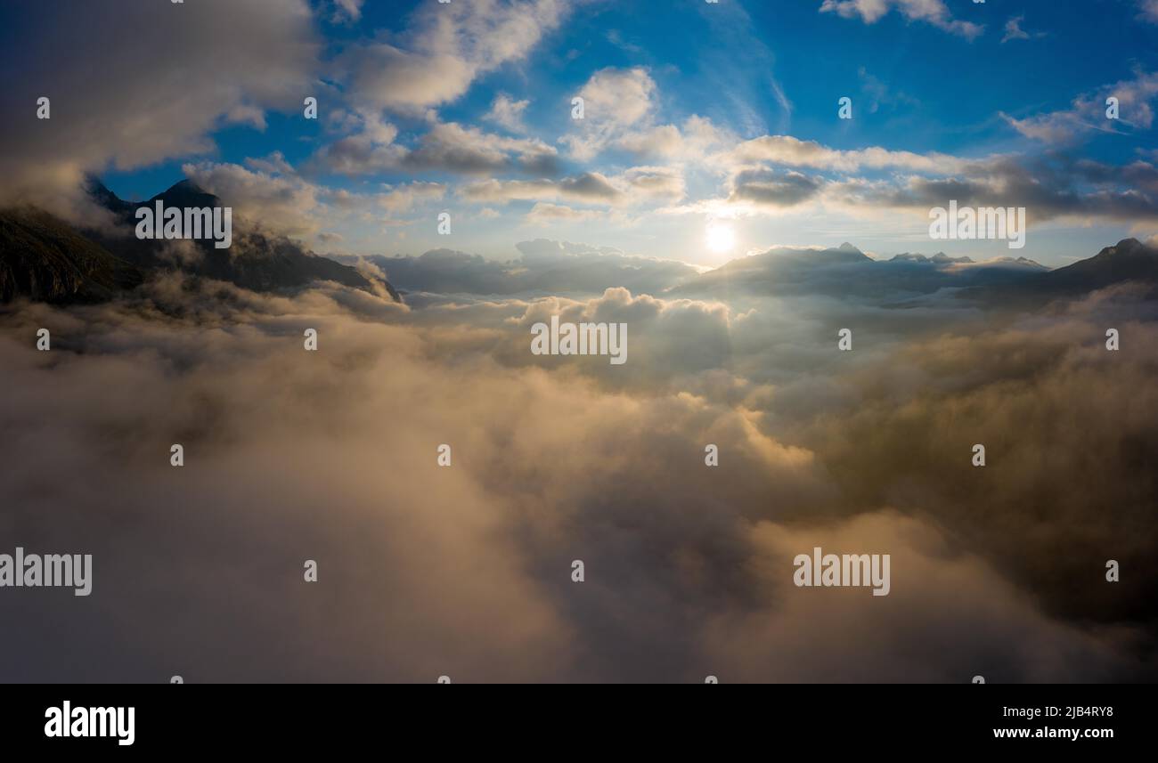 Aerial view above the clouds at sunrise, high above the Urseren Valley towards the Oberalp Pass with the Uri Alps, Canton Uri, Switzerland Stock Photo