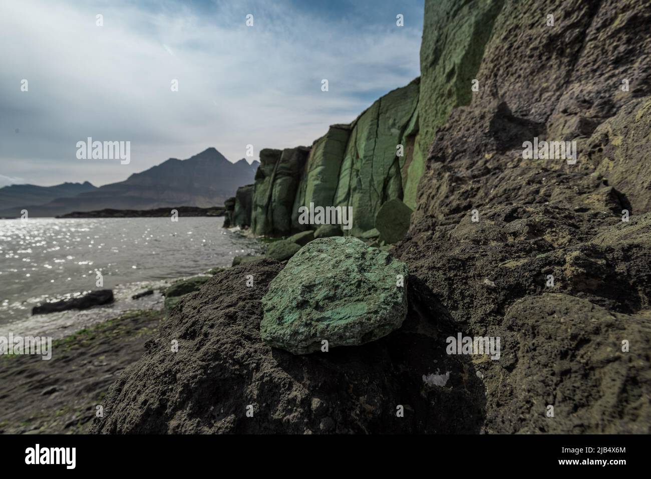 Green ignimbrite rock formations on the beach in southern iceland. Volcanic conglomerate with boulders and cobbles around. Stock Photo