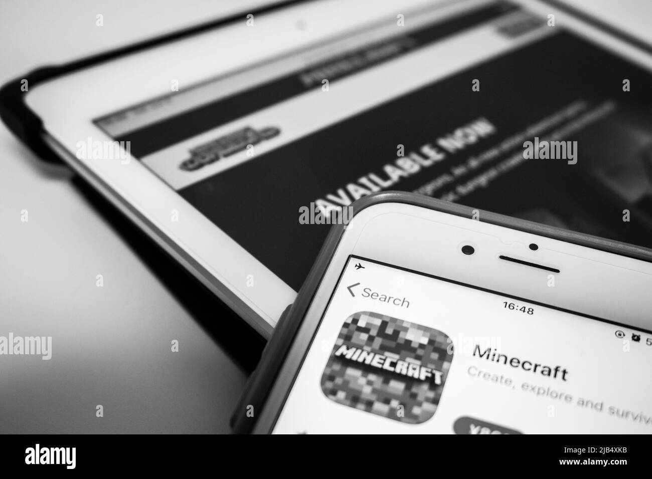 Minecraft in App Store on iPhone and Minecraft Dungeons on iPad in monochrome. Minecraft is a sandbox video game by Mojang Studios Stock Photo