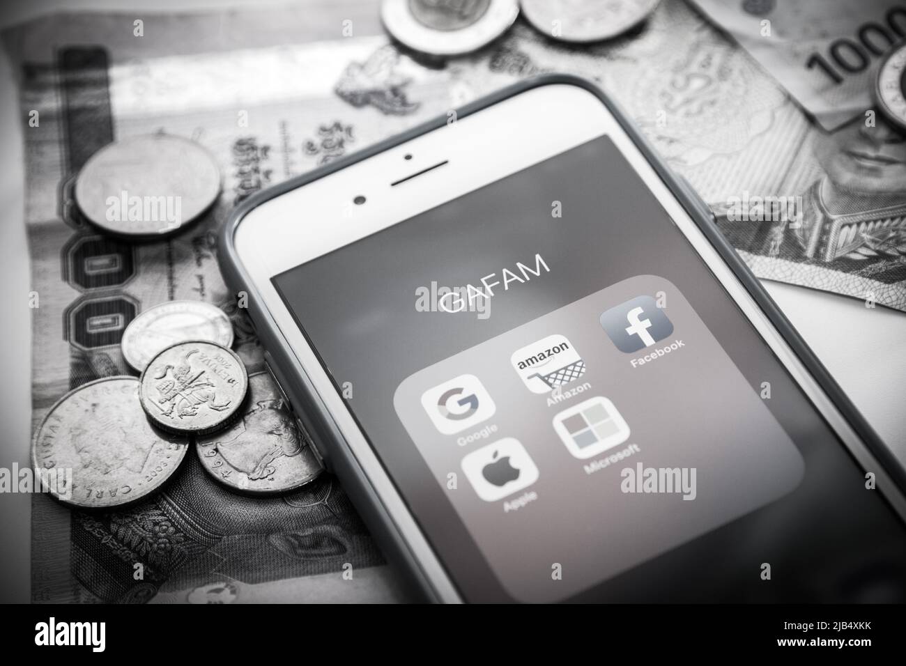 GAFAM on iOS with coins & bills in monochrome colour. Google, Amazon, Facebook, Apple & Microsoft are 5 US IT companies dominated cyberspace in 2010s Stock Photo