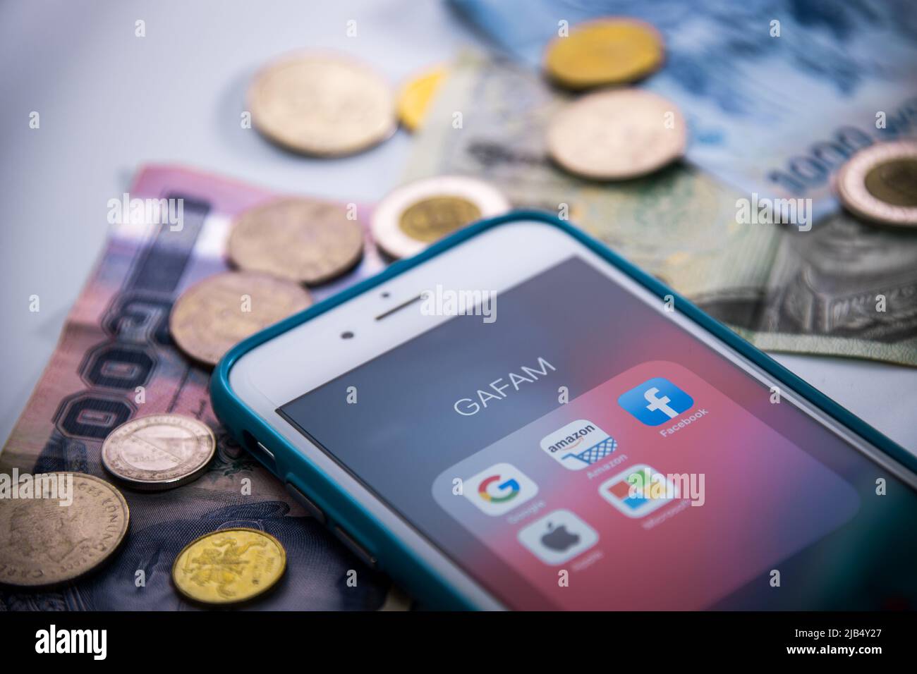 GAFAM on iPhone with coins & bills. Google, Amazon, Facebook, Apple & Microsoft are 5 US IT or online service companies dominated cyberspace in 2010s Stock Photo