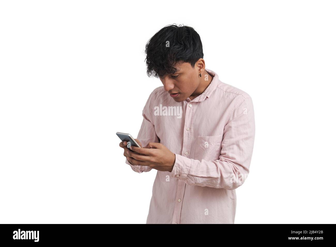 Young peruvian man surprised using the smartphone, isolated. Stock Photo