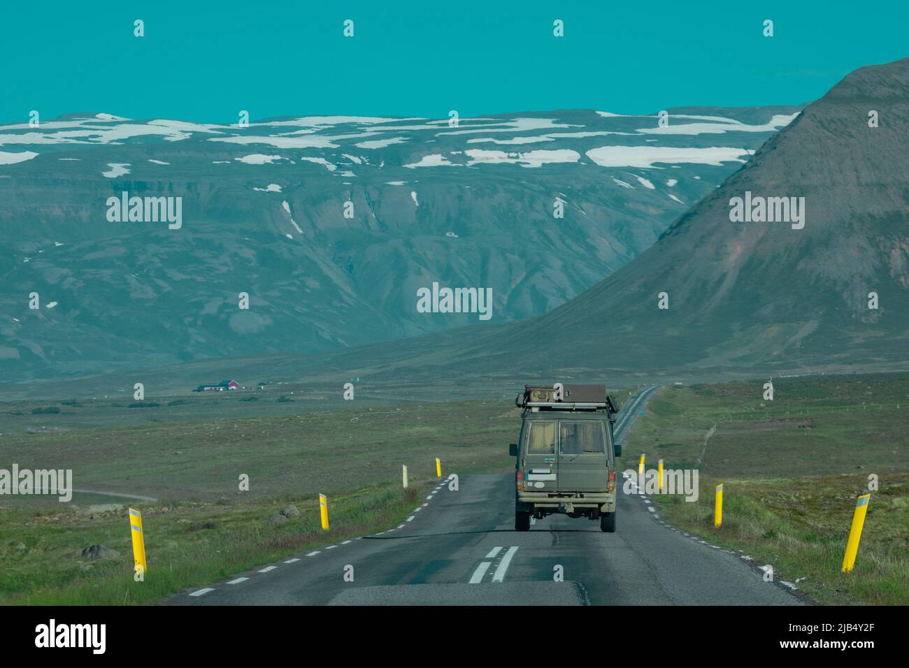 Rear view of an adventure offroad vehicle traveling through icelandic roads towards the mountains. Epic roadtrip with a car or overlanding vehicle. Stock Photo