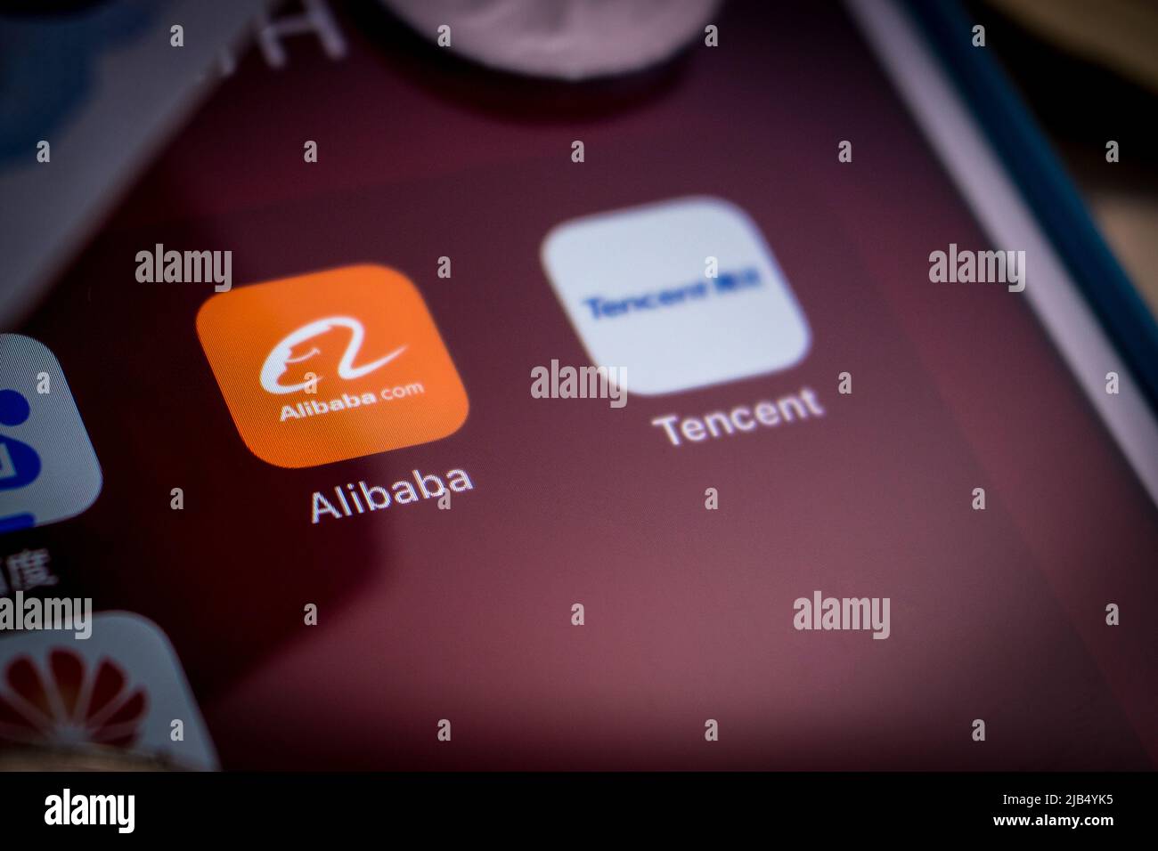 Alibaba logo, founded on 4 April 1999 in Hangzhou, Zhejiang, with Chinese big tech company logos (Baidu, Tencent and Huawei) & money on an iPhone Stock Photo