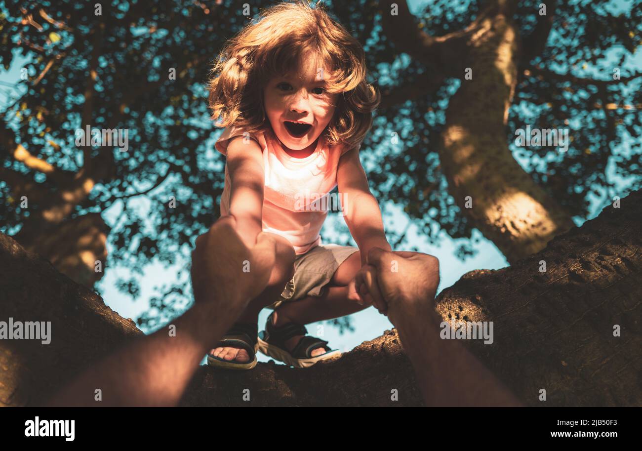 Kids climbing trees. Fathers hand. Child protection. Stock Photo