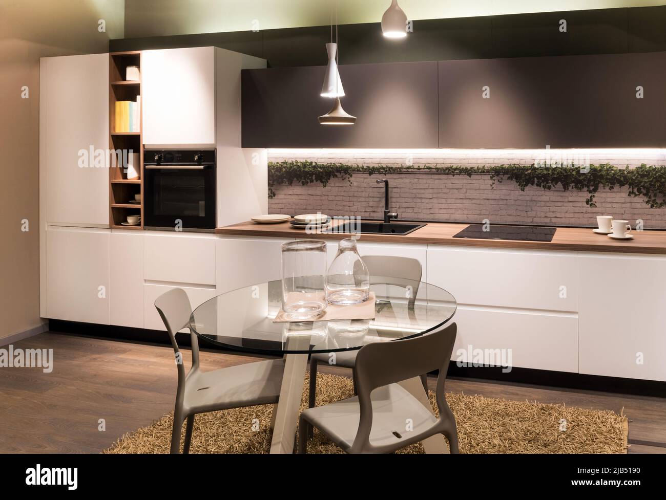 Round glass table with glassware and chairs located near cupboards and